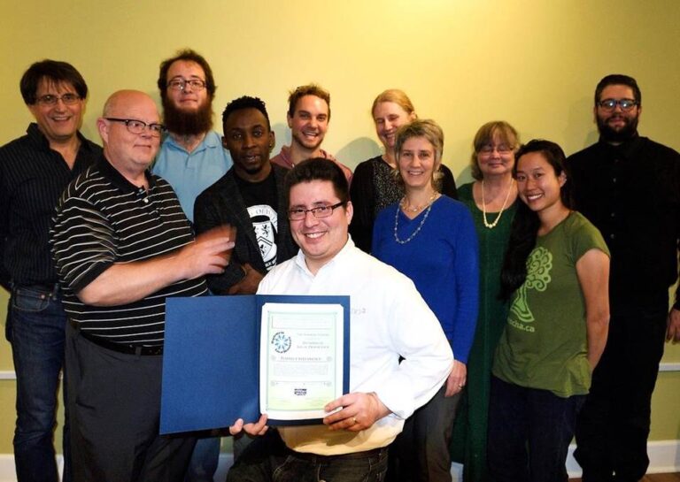 A group of participants of the Local Democracy class stand together. One member holds a certificate of completion